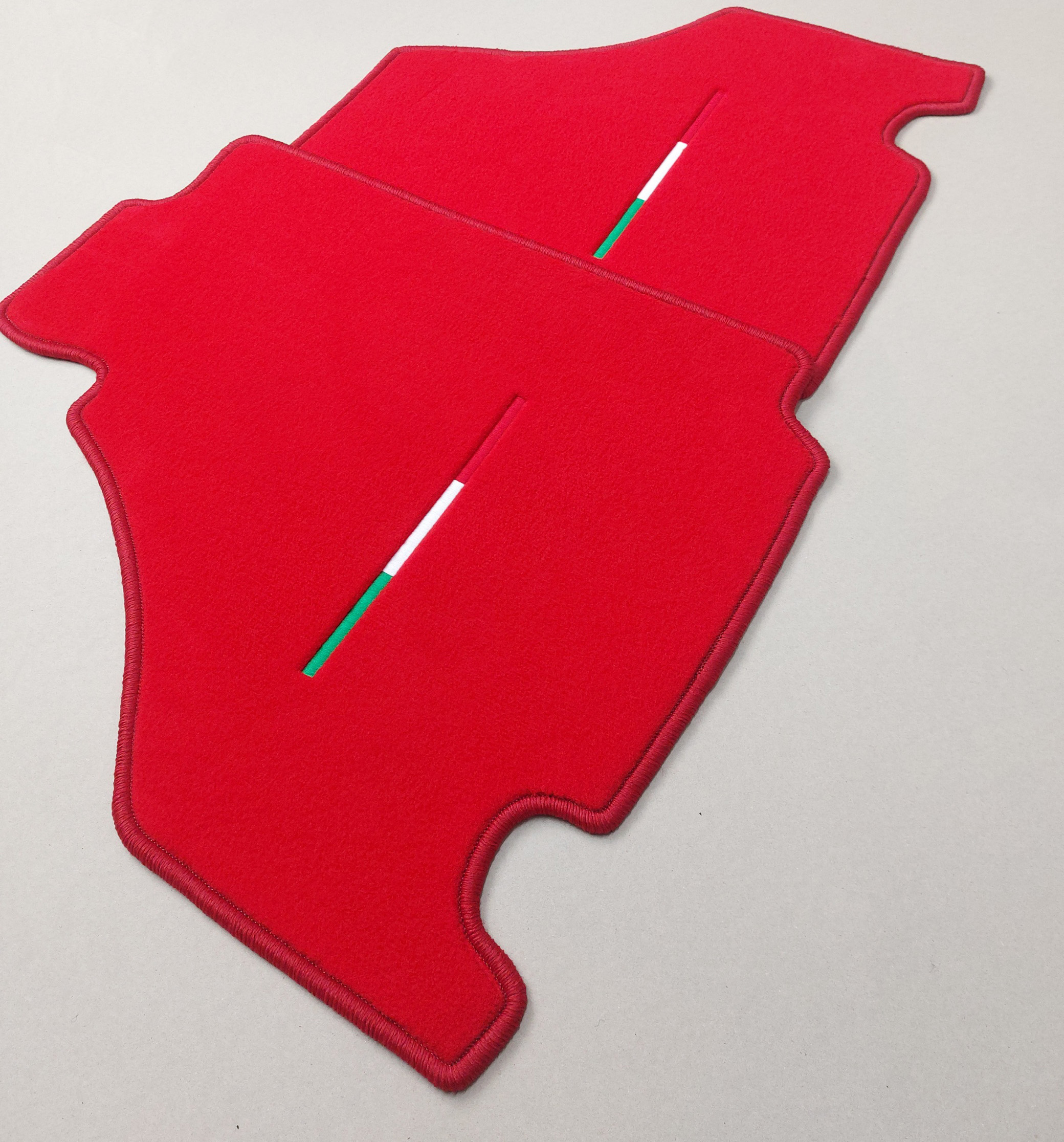 Zwei Fussmatten fuer einen Ferrari in rot mit Tricolore Stick seitliche ansicht.